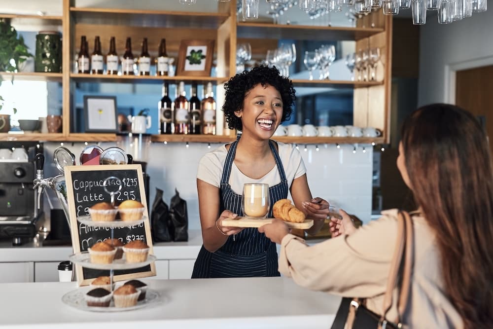 A coffee shop working serving a customer.