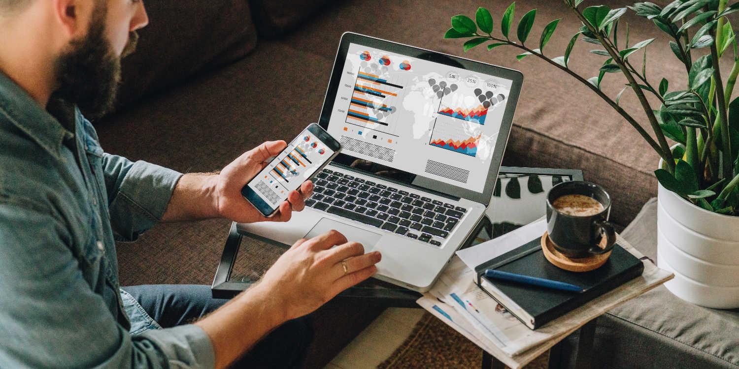 Man looking at charts on his phone and computer