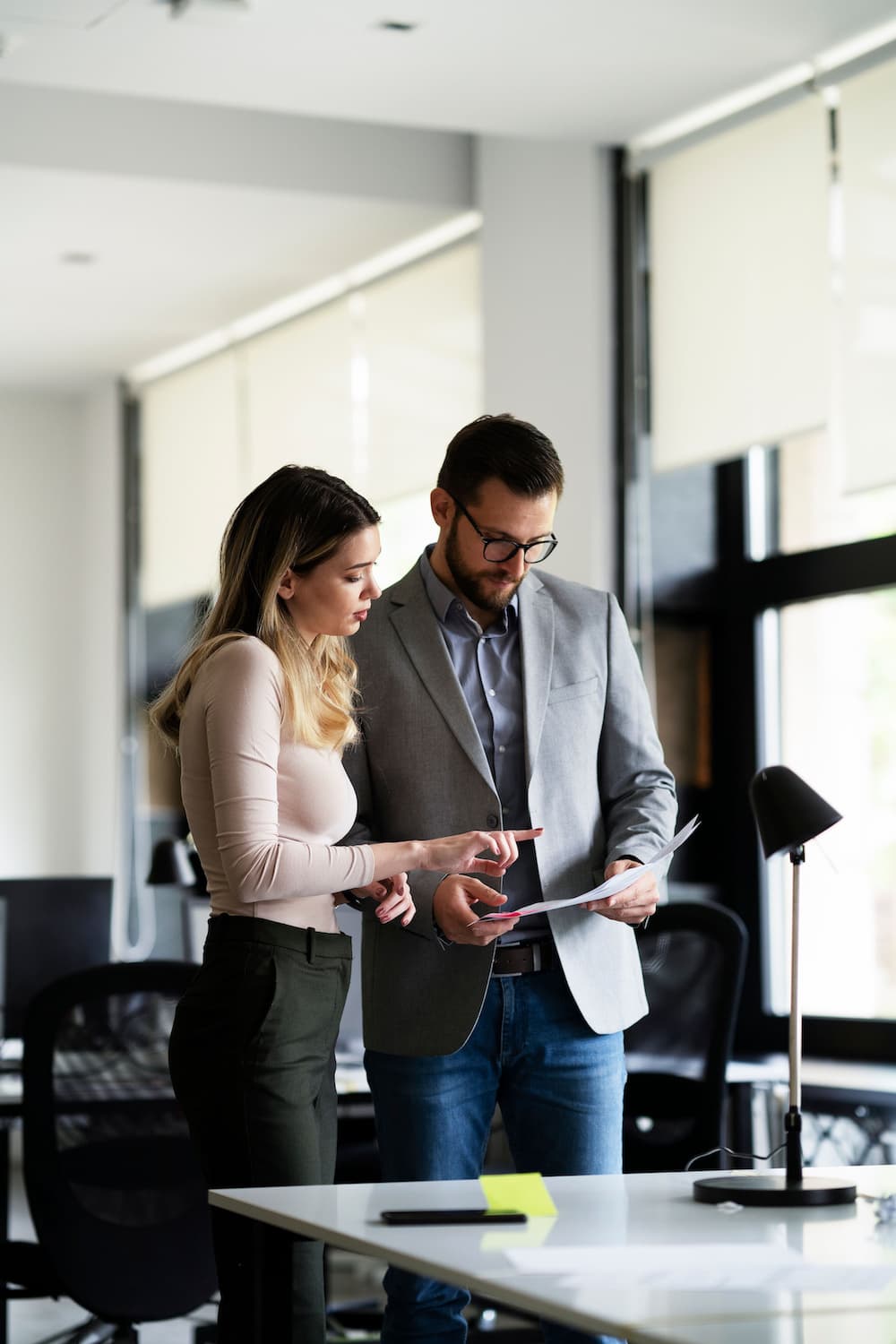 A man and a woman standing in an office with a computer